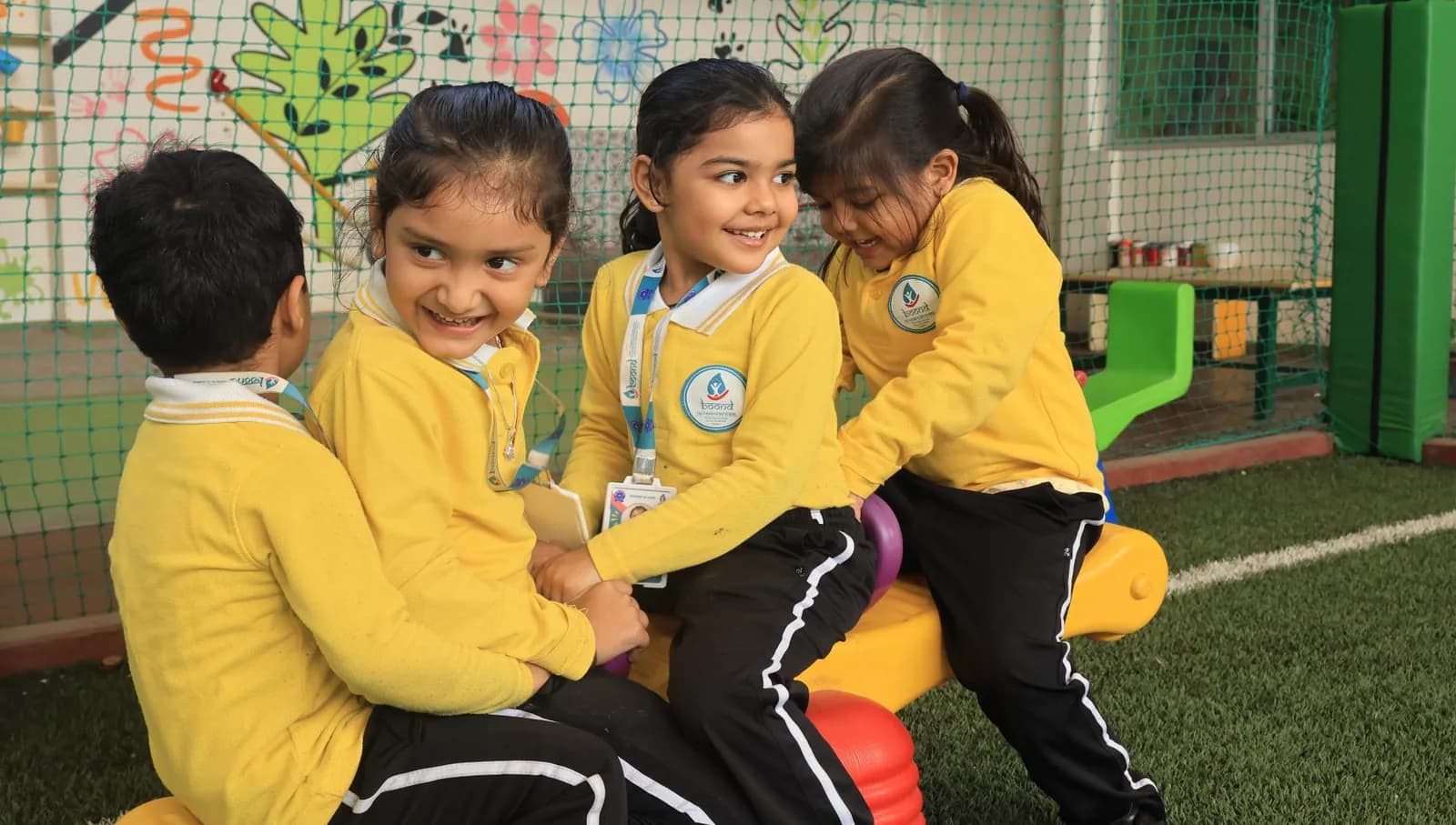 Four children in yellow jerseys playing together on outdoor equipment