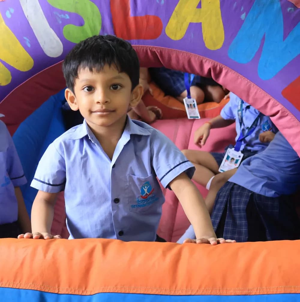 A child smiling from inside a soft play tunnel