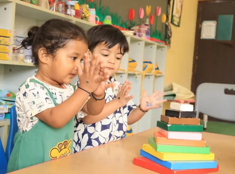 Two toddlers clapping with paint on their hands during a sensory play session