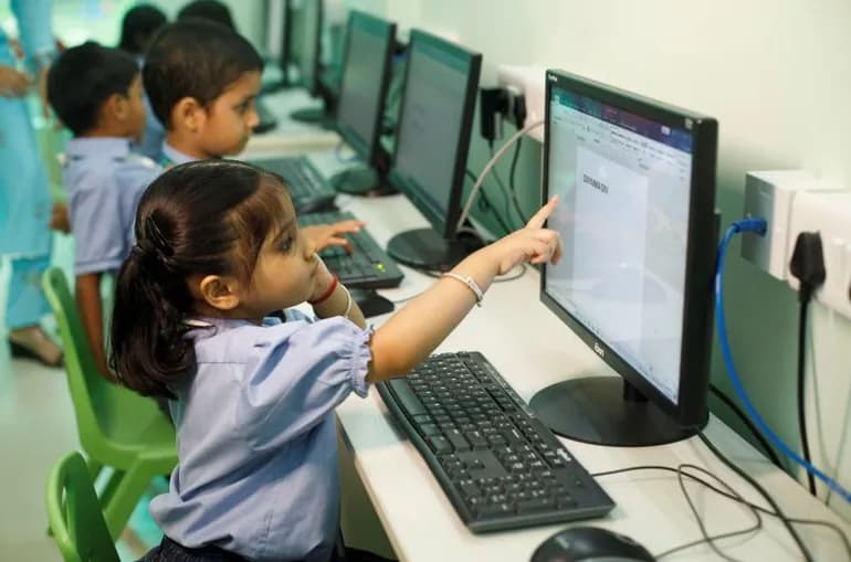 A young child using a desktop computer in the junior computer lab
