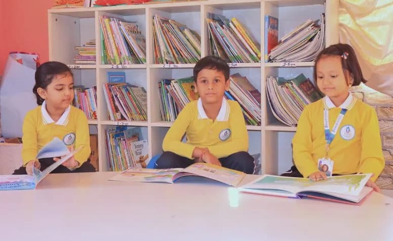 Three children reading picture books in the junior library