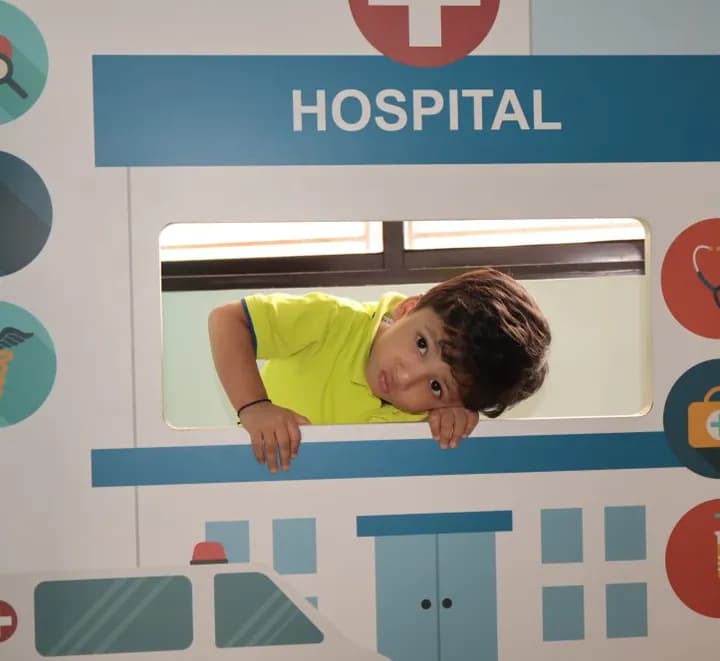 A child at the window of the hospital role-play unit in the Explorers Den