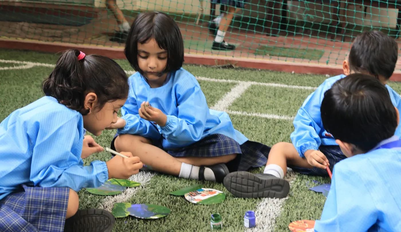 Children painting with natural materials on the school lawn