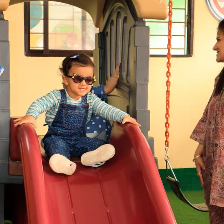A toddler at the top of a play slide