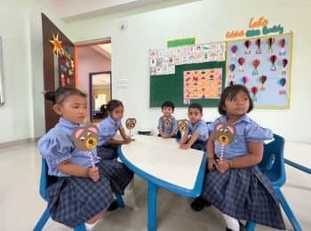 Boond children seated at a class table with craft puppets