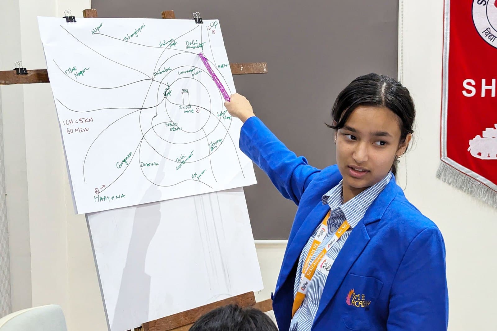 A Sri Sri Academy Siliguri student presenting her group's plan on a flip chart