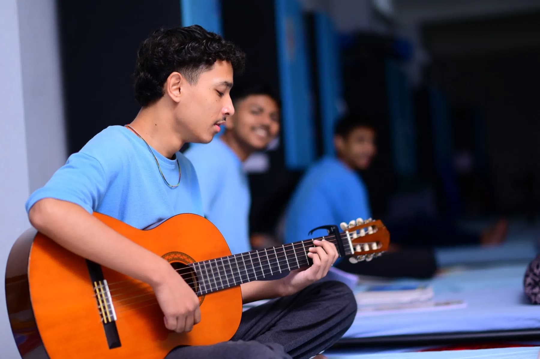 A boarding student playing guitar at Sri Sri Academy